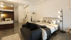 A modern bedroom with a bunk bed, a sofa, a bedside table, and a floor lamp. - Loft Series (Krabi)