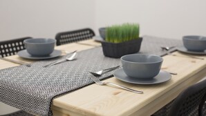 A dining table with grey bowls, spoons, and a patterned placemat. - Loft Series (Krabi)