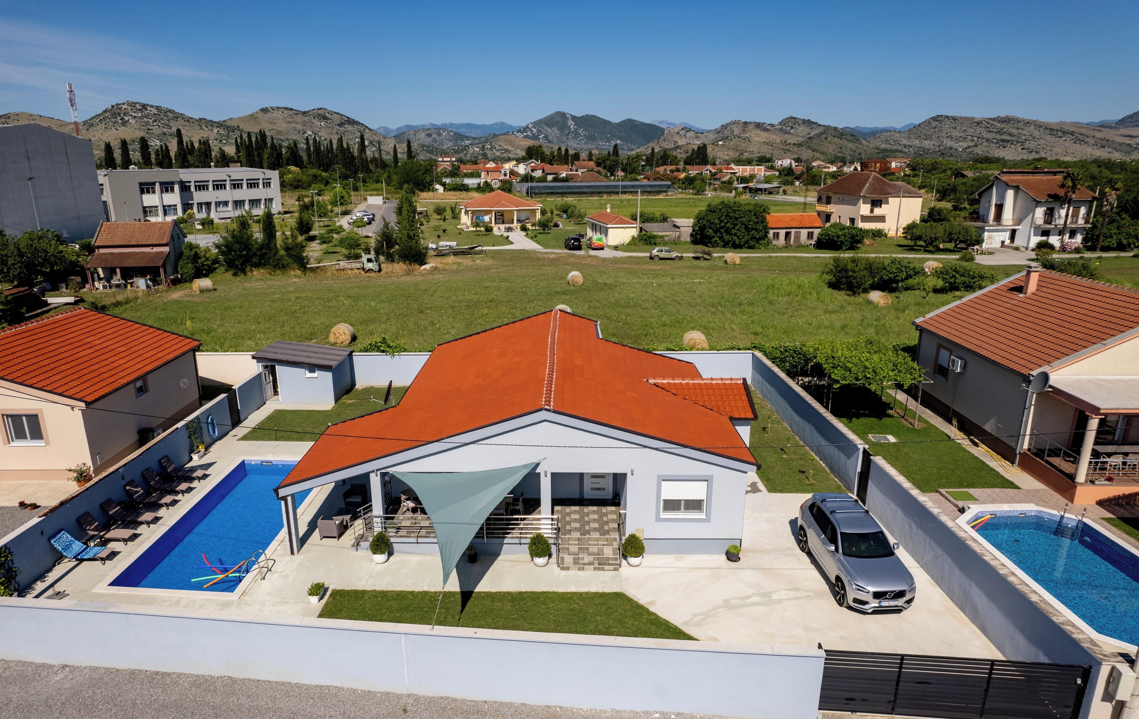A residential area with houses, a swimming pool, and a view of mountains.