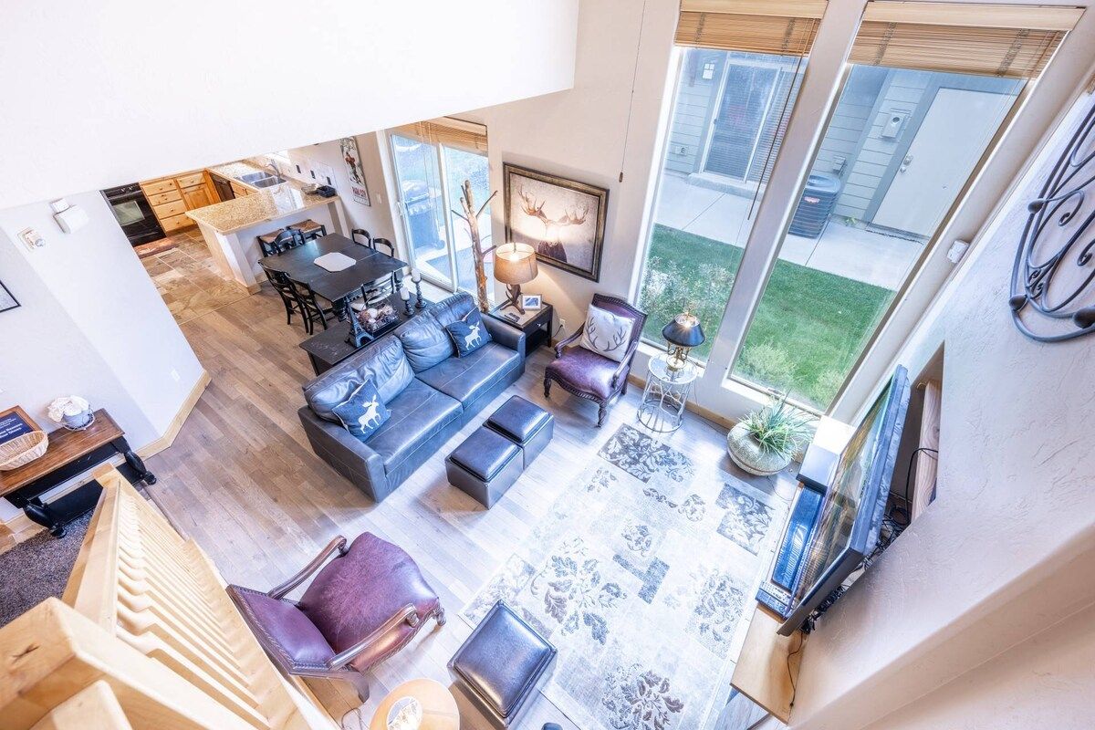 A spacious living area with a sofa set, a dining table, and a kitchen in the background.