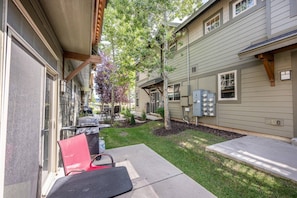A residential property with a covered patio, outdoor seating, and a well-maintained lawn.