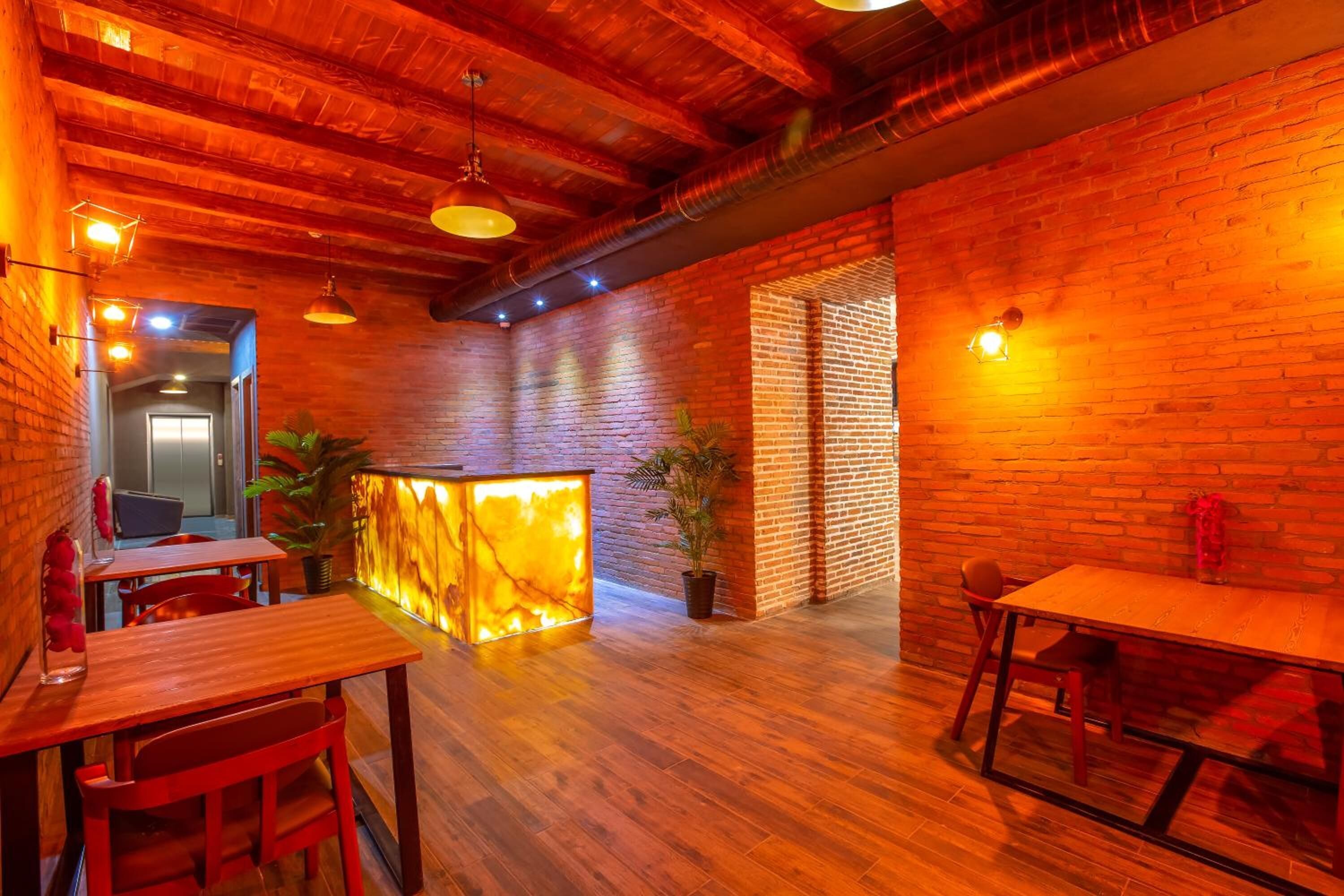 Ein Restaurant mit Holztischen und -stühlen, einer Ziegelwand und einer Holzbalkendecke.