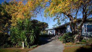 A pathway leading to a building with a porch, surrounded by trees with autumn foliage. - Rural South Wairarapa Home - Views,Swimming & Spa Pool (Taumata Island)