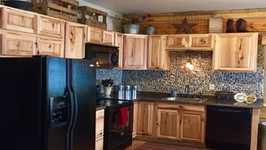 Eine Küche mit Holzausstattung, einem schwarzen Kühlschrank, einem Herd und einem Spülbecken.