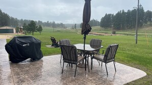 Eine möblierte Patio mit Grill, Tisch und Sonnenschirm.
