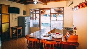 Une cuisine avec des meubles en bois, un réfrigérateur et un téléviseur fixé au mur.