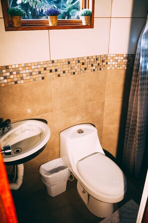 Un baño con lavamanos, inodoro y un revoque de azulejos.