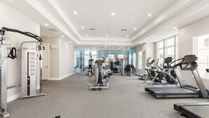A gym with cardio machines, weight training equipment, and a mirrored wall. - ★Amazing Hidden Gem | Min ➡️ Disney | ❤ 139 (Kissimmee)