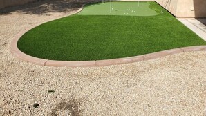 En trädgård med konstgräs, en puttinggreen och ett område med grus.