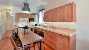 Een moderne keuken met houten kastjes, een eettafel en een hanglamp.