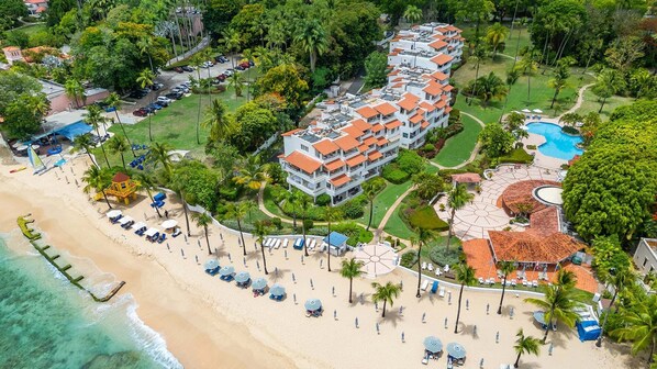 Un complexe hôtelier doté d’une plage, d’une piscine et d’un bâtiment comportant de nombreux balcons.