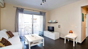 A modern living room with a sofa, a coffee table, a TV on a white cabinet, and a lamp on a side table. - Gabriel 01 by Interhome (Calpe/Calp)