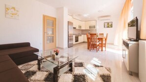 Eine moderne Wohnung mit Wohnzimmer, Essbereich, Küche und Fernseher.