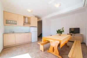Une cuisine de taille réduite comprenant un coin repas, un téléviseur et une plante en pot.