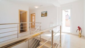 Ein modernes Interieur mit einer Treppe, einer Tür zu einem anderen Raum und einer Vase mit Blumen.