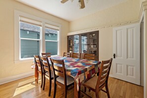 A dining room with a wooden table, chairs, a quilt, and a cabinet with glass doors. - Victorian Charm + BBQ Yard | Paso Robles Wine Country | Vacations on Vine (Paso Robles)