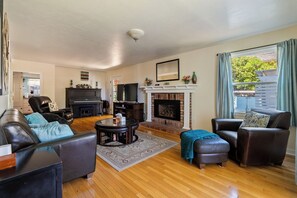 A living room with a fireplace, leather sofas, a coffee table, and a TV. - Victorian Charm + BBQ Yard | Paso Robles Wine Country | Vacations on Vine (Paso Robles)