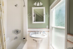 A bathroom with a bathtub, a sink, a mirror, and a window. - Victorian Charm + BBQ Yard | Paso Robles Wine Country | Vacations on Vine (Paso Robles)