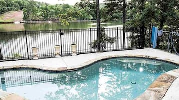 Una piscina de vora corba, envoltada per un terra de pedra i una tanca de metall.