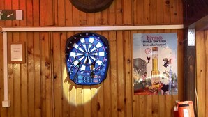 A dartboard, a poster, and a wooden wall in a room. - Whole basement former pub 4 stag do (VIII. kerület)