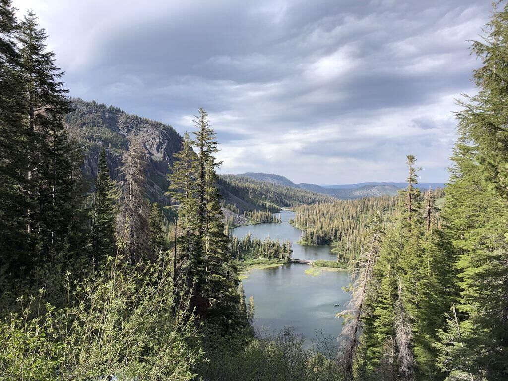 A mountainous landscape with a lake surrounded by dense forests.