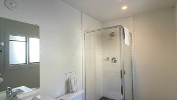 A bathroom with a shower, toilet, sink, and a mirror.