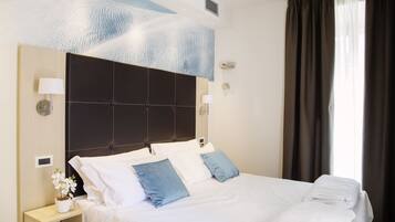 A hotel room with a large bed, two bedside lamps, a nightstand with a lamp and a small potted plant, and a ceiling with a textured design.