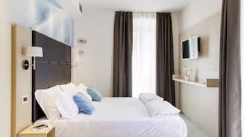 A modern hotel room with a large bed, a flat-screen TV, a bedside table, and a wall-mounted shelf with a vase.