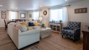 Ein Wohnzimmer mit einer Couch, einem Sessel und einem Essbereich mit Tisch und Stühlen.
