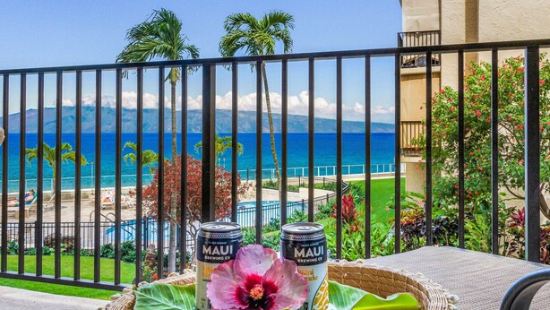 Ein Balkon mit Blick auf das Meer und einen Pool, mit zwei Bieren von Maui Brewing Co. und einer Zierblume.