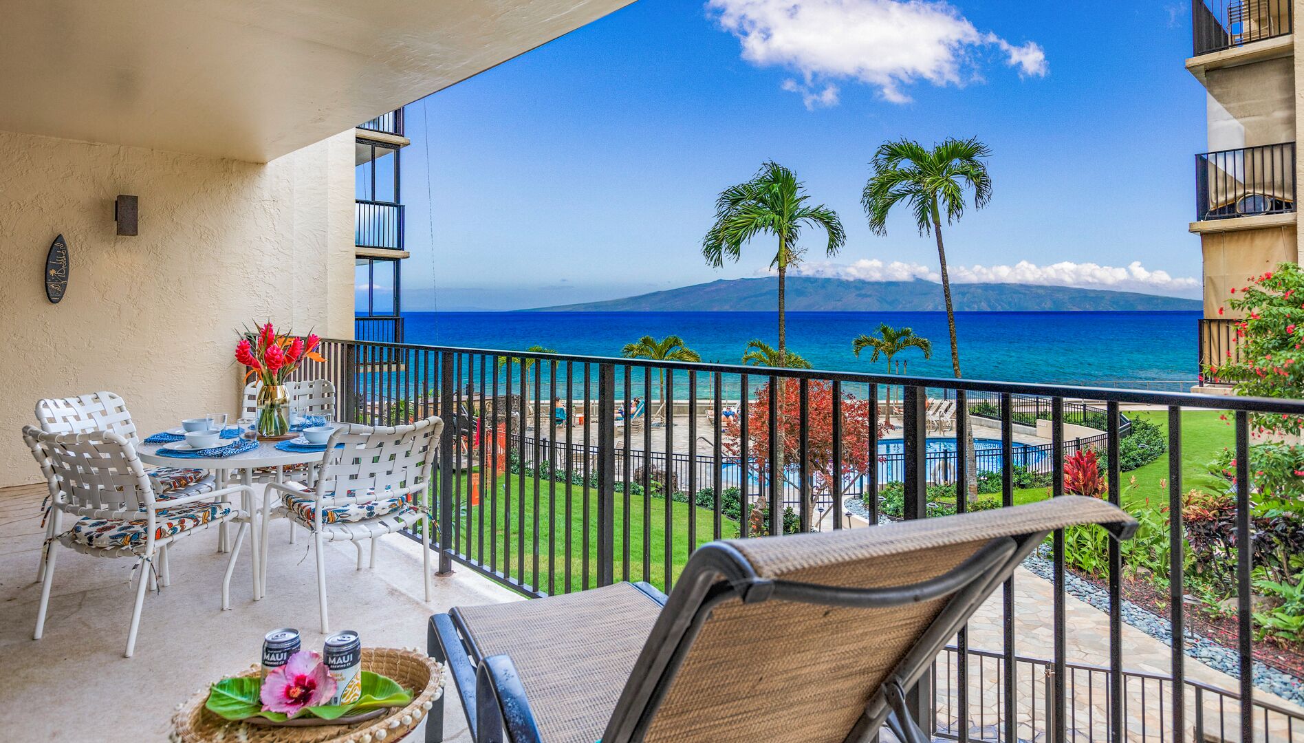 Un balcon avec une table dressée pour deux personnes, donnant sur une piscine et offrant une vue sur l’océan.