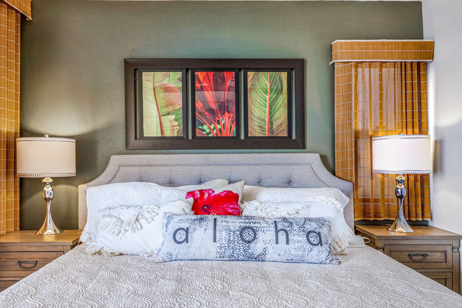 Une chambre à coucher bien rangée, avec un lit, deux tables de chevet et une œuvre d’art encadrée au-dessus du lit.