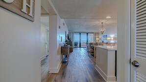 A spacious kitchen with a central island, a dining area with chairs, and a view through the glass door.