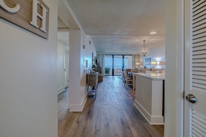 A spacious kitchen with a central island, a dining area with chairs, and a view through the glass door.