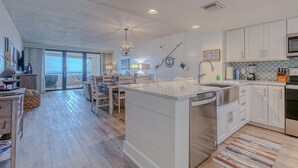 A modern kitchen with white cabinetry, a central island with a sink, and a dining area with chairs.