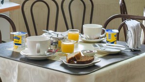 Et morgenbord med kaffekop, juice, krukke med honning, et stykke brød og et smørbord.