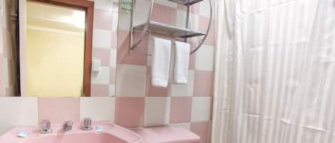 Un baño con lavamanos, inodoro y cortina de ducha rosa.