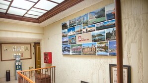 Et hotellobby med en trappe, en væg udsmykket med forskellige fotografier, og et skilt for Hotel Sahara Inn.