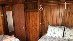 Ein Zimmer mit Holzboden, zwei Betten, einem Kleiderschrank und einem Kleiderhaken.