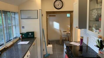 A kitchen with a washing machine, a broom, and a first aid kit.
