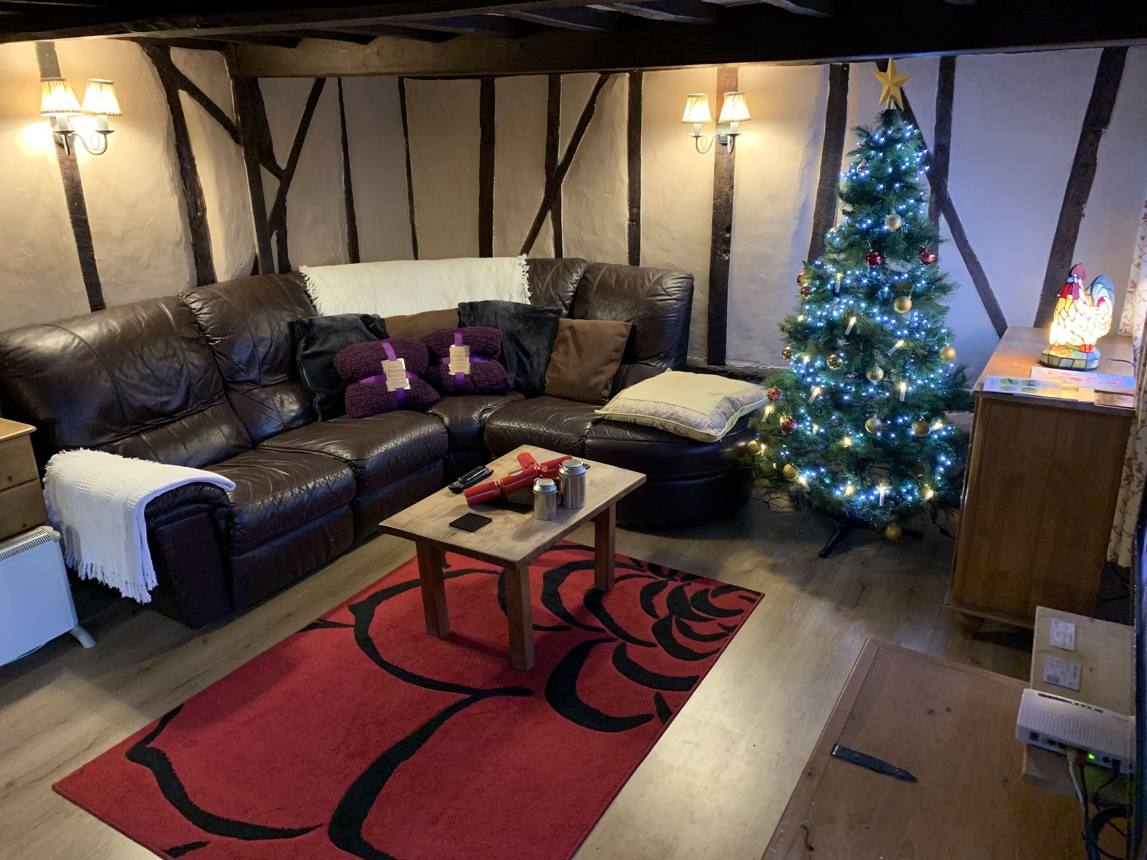 A cozy living room with a leather sofa, a coffee table, and a Christmas tree.