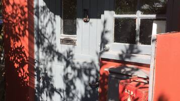 A cottage entrance with a sign reading "Myrtle Cottage," a wooden door, and a small table with a red object on it.
