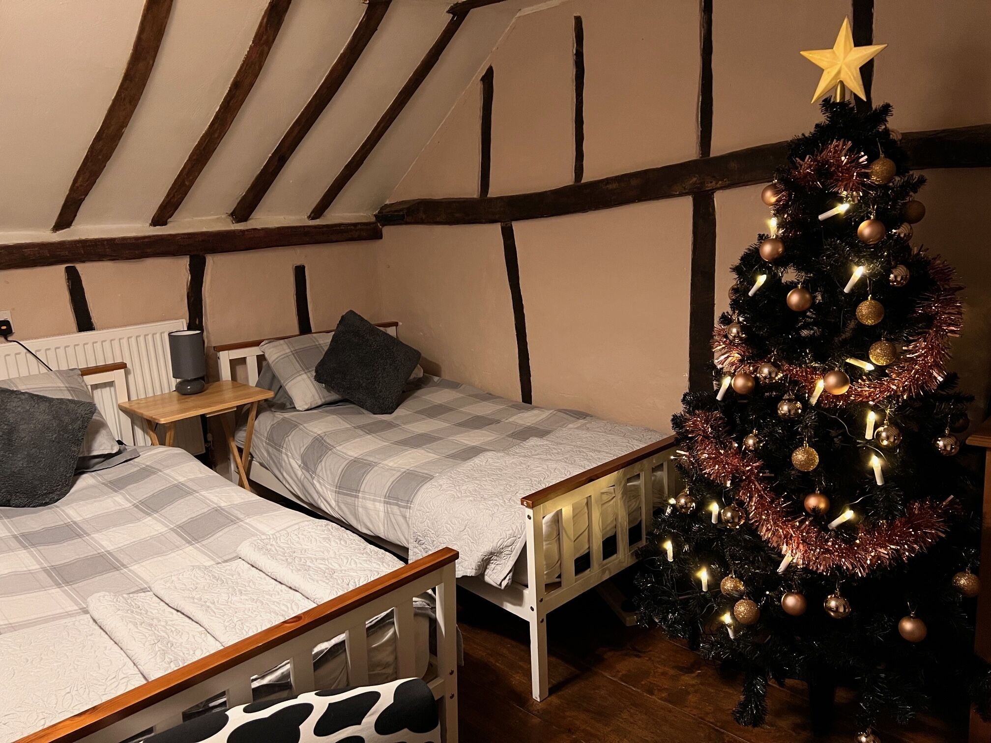 Une chambre confortable avec deux lits, un plafond en bois et un sapin de Noël décoré.