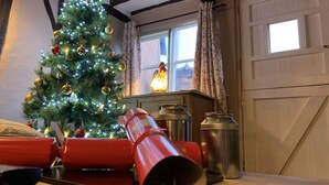 A room with a Christmas tree, a window with curtains, and a door. - Myrtle Cottage (Diss)