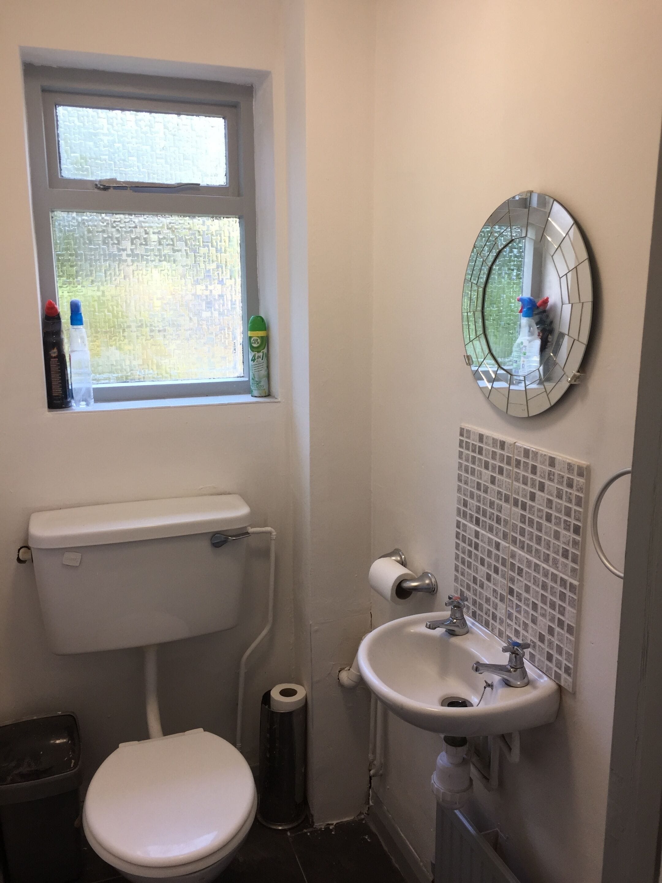 Ein kleines Badezimmer mit Toilette, Waschbecken und Fenster.