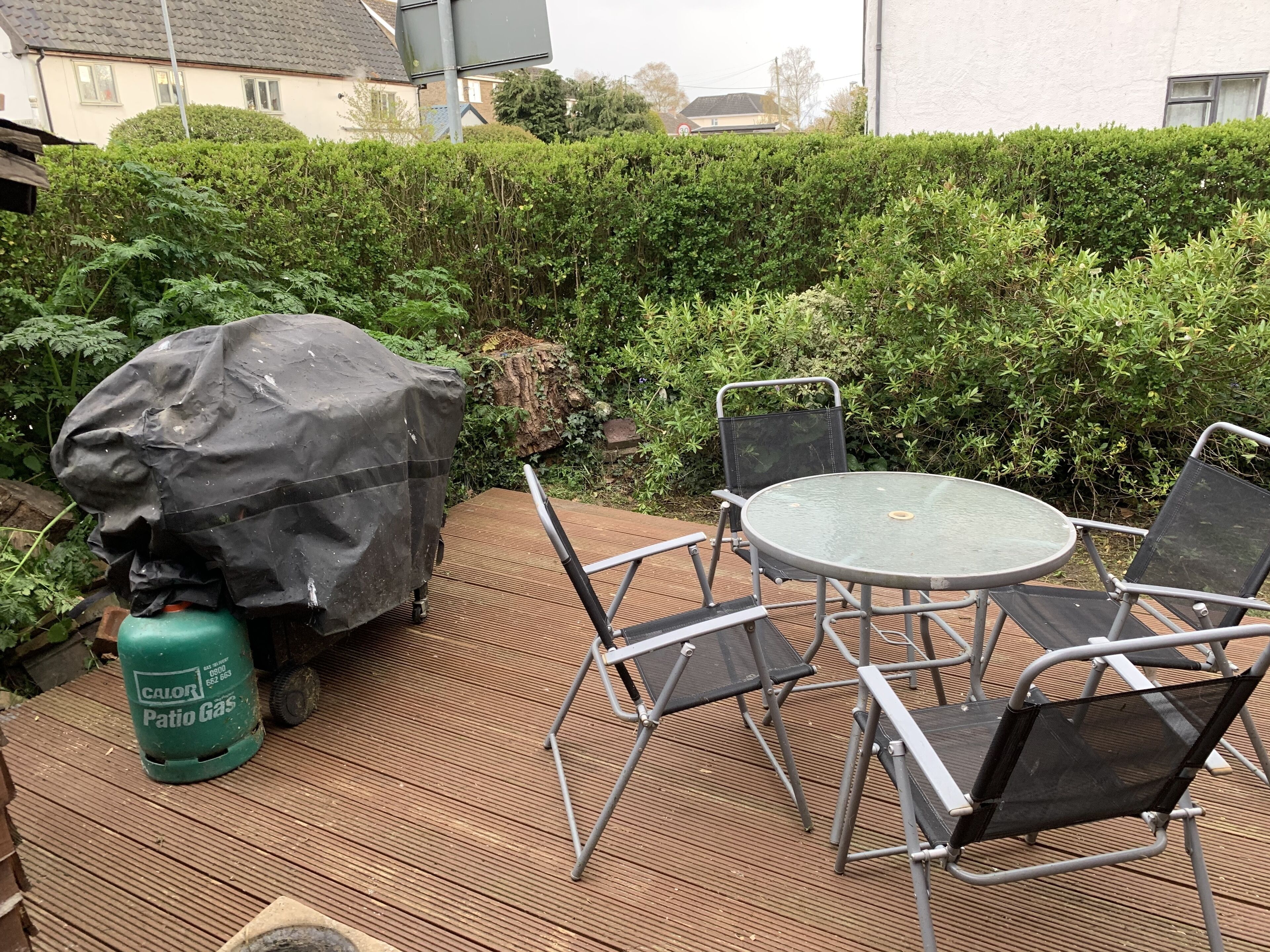 An outdoor patio area with a covered grill, a round table, and four chairs.