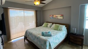 Quarto com cama, ventilador de teto, janela com persianas e um quadro na parede.