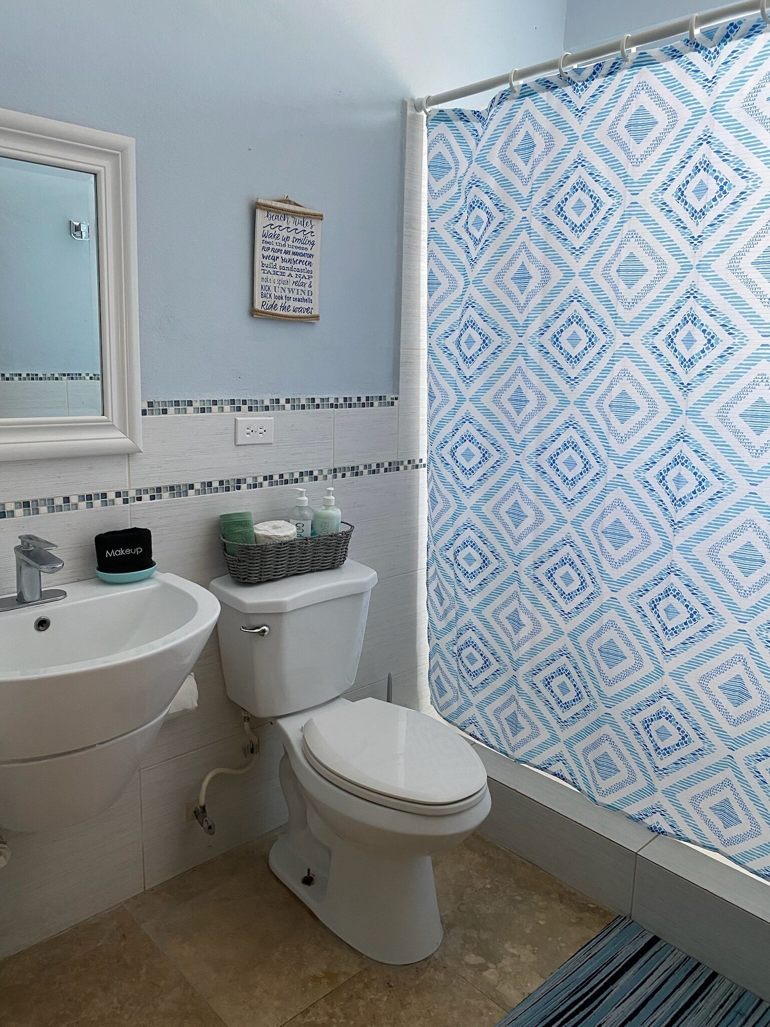 Une salle de bain équipée d’un lavabo, de toilettes et d’un rideau de douche à motifs géométriques.