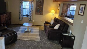 A living room with a sofa, a coffee table, a lamp, and a TV.
