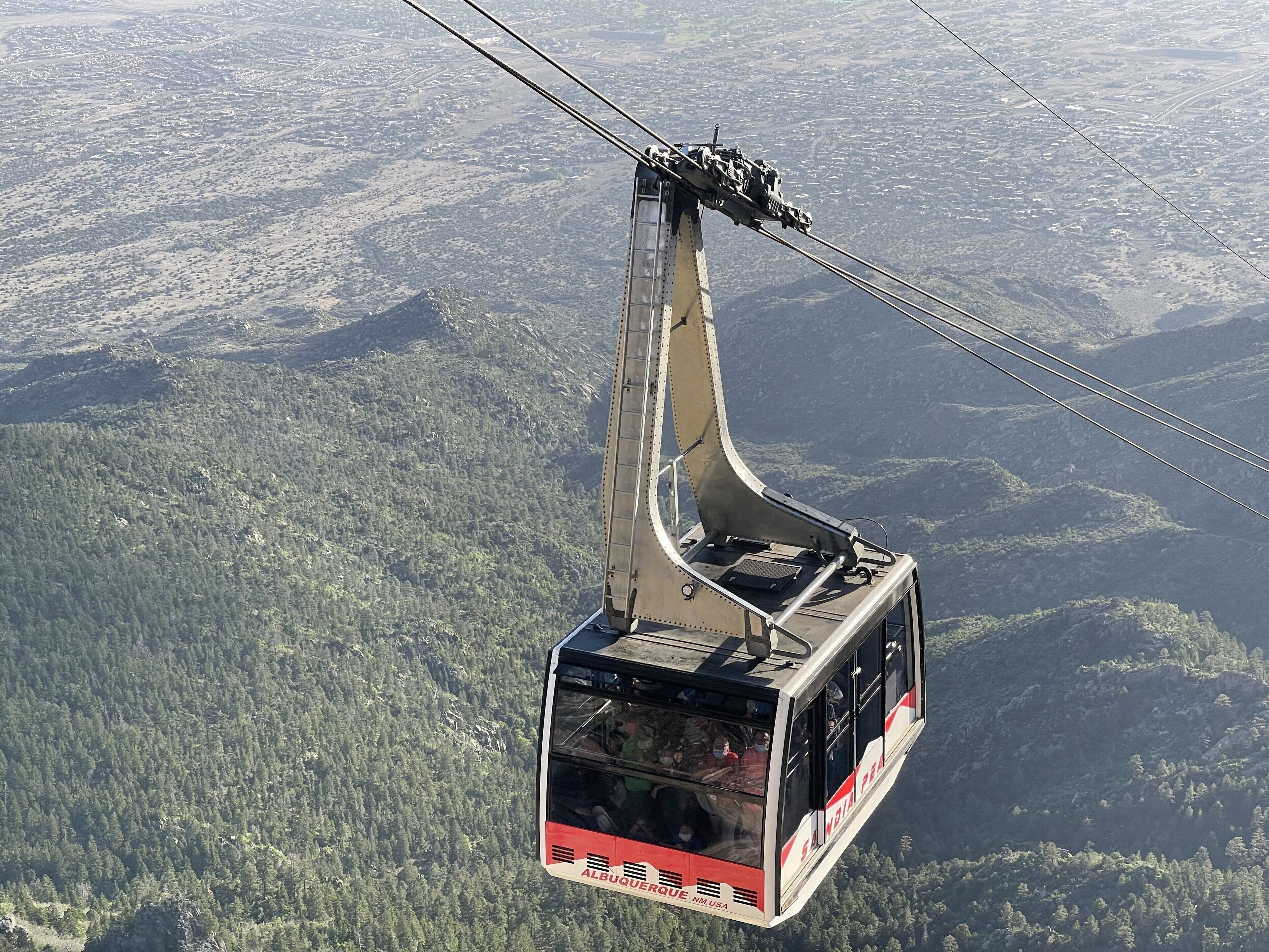 Een kabelspoorweg hangt boven een bergachtig landschap.